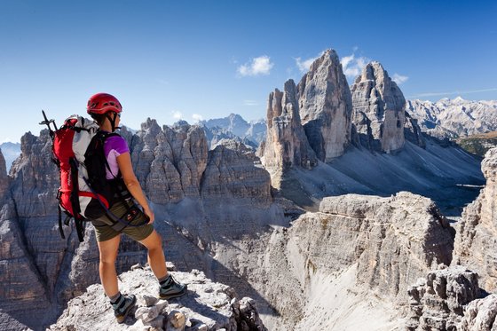 Arrampicata in Alto Adige: si sale in alta quota! Escursionista con casco guarda le Tre Cime di Lavaredo nelle Dolomiti