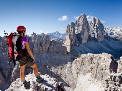 Klettern im Rosengarten: Rotwand- und Masarè-Klettersteig Wanderer mit Helm blickt auf die Felsen der Drei Zinnen in den Dolomiten