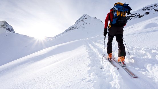 Skitour auf das Astjoch Skifahrer mit Rucksack steigt an sonnigem Tag einen schneebedeckten Berg hinauf