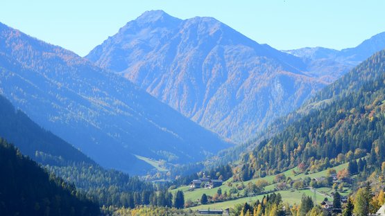 Der Zoggler-See im Ultental Bergsee mit Wald und Hütten im Herbst unter klarem Himmel