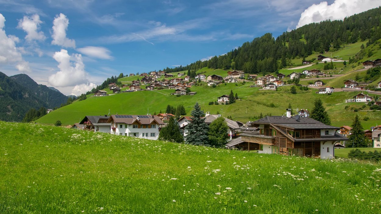 Hotel a Santa Cristina in Val Gardena Prati verdi con case ai piedi di colline boschive sotto un cielo blu