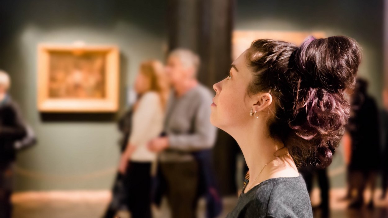 Wiesen, Wälder, Wein – Kloster Neustift in Südtirol Frau betrachtet Ausstellung im Museum, unscharfer Hintergrund mit anderen Besuchern