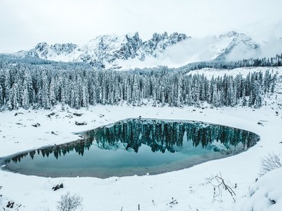 Lavazè Pass - Lieg Alm Schneebedeckter Bergsee mit reflektierenden Tannen und Nebel