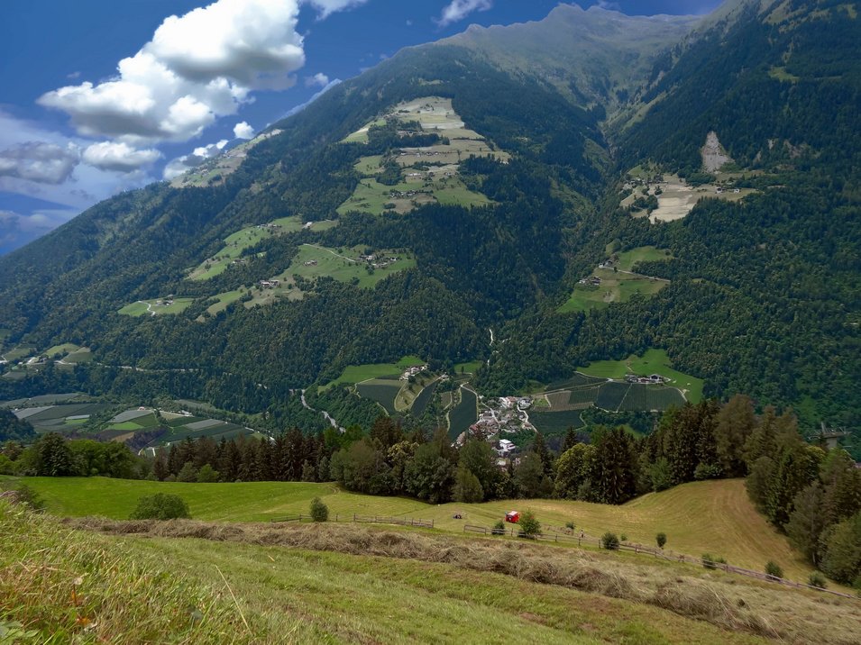 Hotels Saltaus im Passeiertal Berglandschaft mit Tal, Wäldern und Feldern unter blauem Himmel mit Wolken