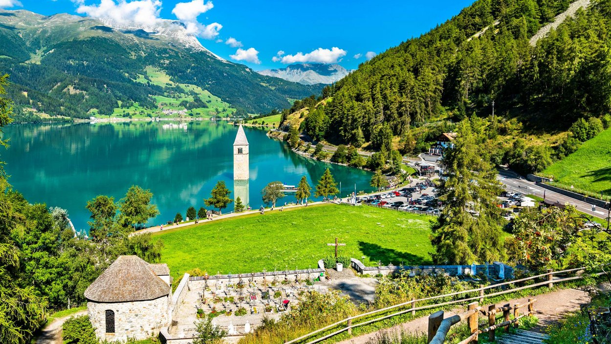 Vinschgau – das wahre Eldorado für Motorradliebhaber Versunkener Kirchturm im See vor Alpenlandschaft und grünem Wald