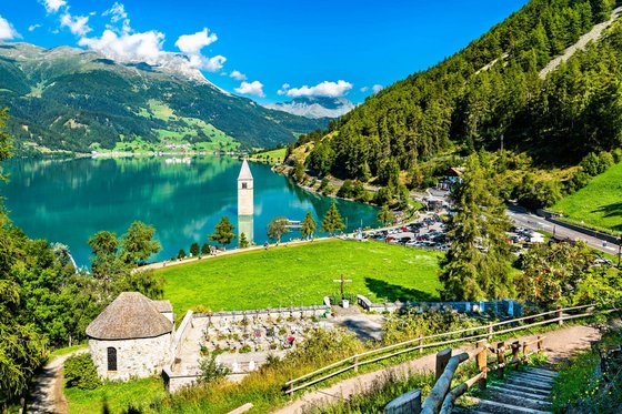 Reschensee: Naturparadies in Südtirol Versunkener Kirchturm im See vor Alpenlandschaft und grünem Wald