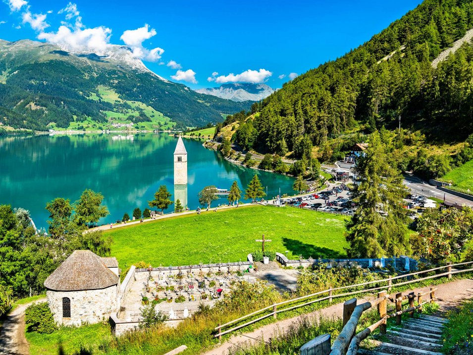 Reschensee: Naturparadies in Südtirol Versunkener Kirchturm im See vor Alpenlandschaft und grünem Wald