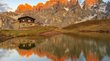 Sul Passo Rolle Rifugio alpino con montagne illuminate dal tramonto e riflesso nel lago