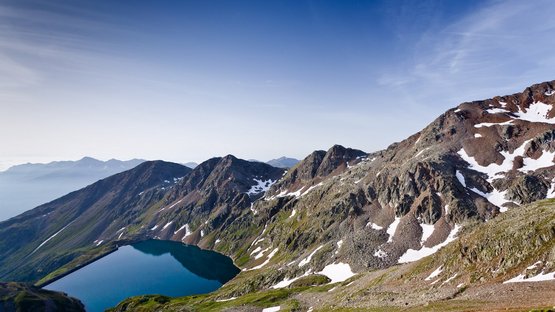 L'Ortles (3.905 m slm) Lago di montagna circondato da montagne rocciose con neve sotto un cielo limpido