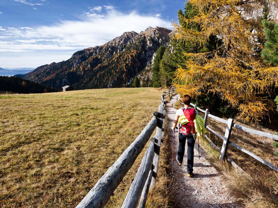 Hotels in Burgstall: der perfekte Ort für Genießer Frau wandert auf Bergweg zwischen Zaun und herbstlichen Bäumen