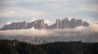 Il Latemar: il gigante dolomitico solitario Foresta davanti a catena montuosa con striscia di nuvole al pomeriggio