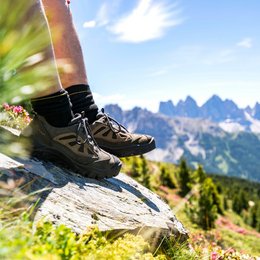 Pischadù-Klettersteig in Südtirol Wanderschuhe auf Felsen mit Bergpanorama und grüner Landschaft im Hintergrund