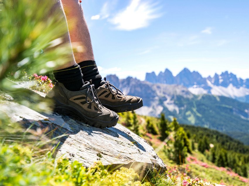 Hotel in Alto Adige 😎☀️ Per vacanze indimenticabili Scarpe da trekking su roccia con panorama di montagne e paesaggio verde sullo sfondo