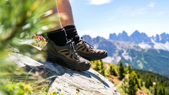 Hotel in Valle Isarco in Alto Adige Scarpe da trekking su roccia con panorama di montagne e paesaggio verde sullo sfondo