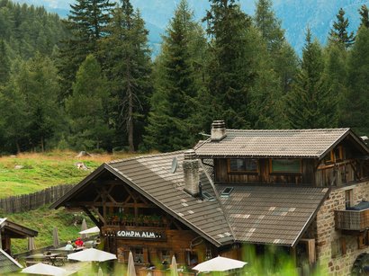 Die Natur in und um Südtirol Berghütte mit Außenterrasse und Bergen im Hintergrund