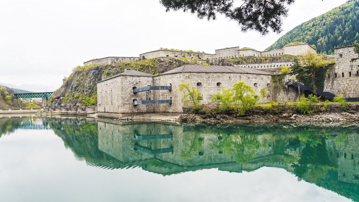 Lago artificiale di Fortezza Antica fortezza sul fiume calmo con montagne e alberi sullo sfondo