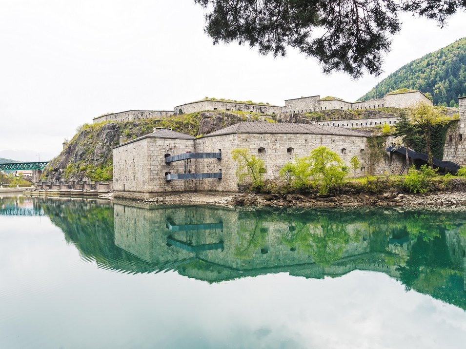 Lago artificiale di Fortezza Antica fortezza sul fiume calmo con montagne e alberi sullo sfondo