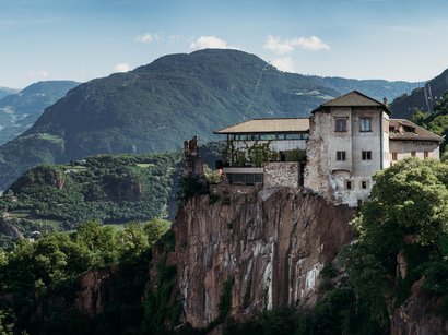 Castel Guardia: soggiornare in una fortezza Antico castello su scogliera con montagne boschive sullo sfondo