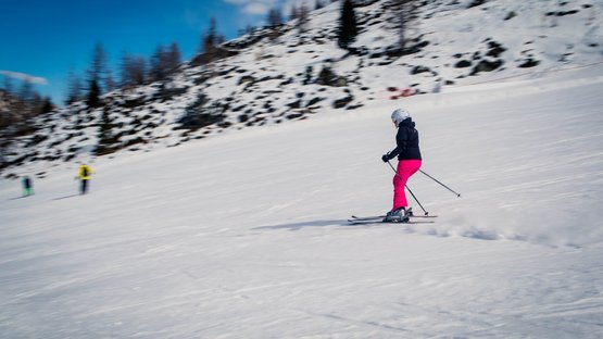 Avventure e piacere nell’area sciistica della Val Senales Scialpinista con pantaloni rosa scende una pista innevata sotto un cielo sereno