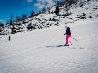 Avventure e piacere nell’area sciistica della Val Senales Scialpinista con pantaloni rosa scende una pista innevata sotto un cielo sereno