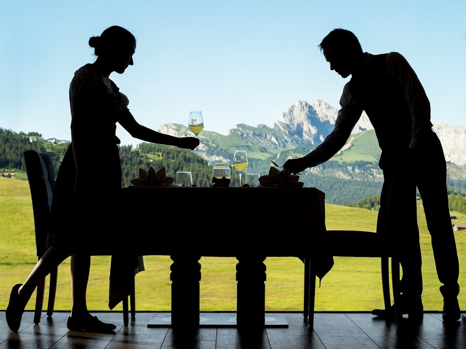 Gourmet-Urlaub in Südtirol: Genuss pur Silhouetten von Kellnern beim Decken eines Tisches mit Bergblick