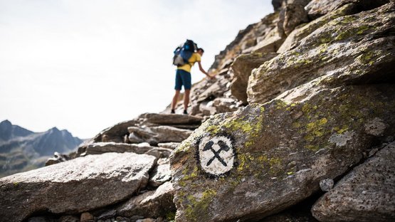 Das Bergbaumuseum am Schneeberg Wanderer mit Rucksack klettert auf felsigem Bergpfad mit Markierung auf Stein