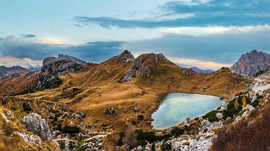 Die Alpenpässe in und um Südtirol Herbstliche Berglandschaft mit See und Wanderwegen unter bewölktem Himmel