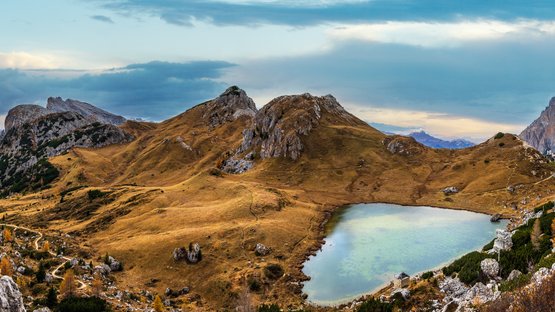 Il sinuoso Passo di Valparola Paesaggio montano autunnale con lago e sentieri sotto un cielo nuvoloso