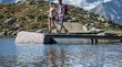 Wandern Südtirol – unvergleichlich schön! Paar wandert auf Brücke über Bergsee mit Bergen im Hintergrund
