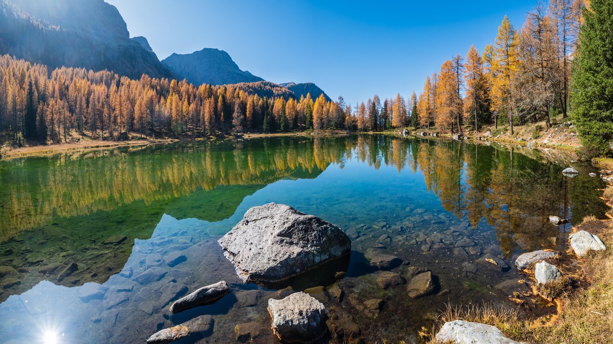 Unterwegs in den Dolomiten Herbstlicher Bergsee mit klarer Spiegelung der bunten Bäume und Felsen im Wasser