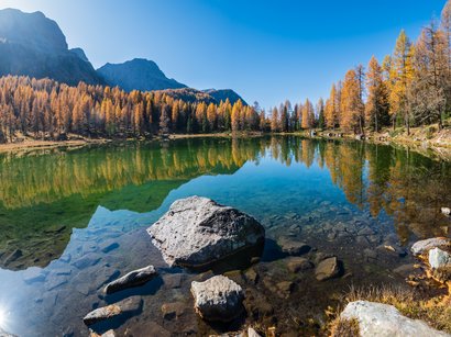 Ihre Hotels nahe der Drei Zinnen im Hochpustertal Herbstlicher Bergsee mit klarer Spiegelung der bunten Bäume und Felsen im Wasser