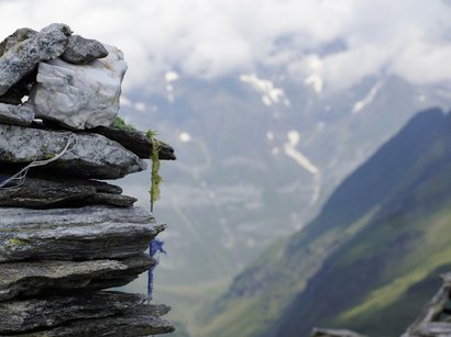 Malghe, 100% Alto Adige Pietre impilate in primo piano con montagne sfocate sullo sfondo