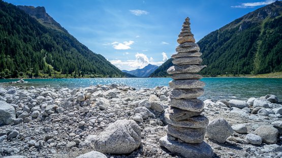 Godetevi il panorama dal Lago di Neves Pietre impilate sulla riva di un lago di montagna con montagne sullo sfondo