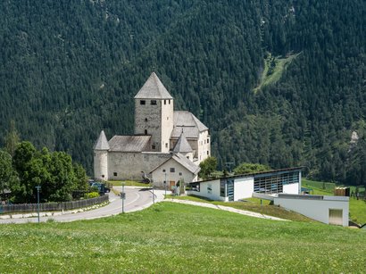 Il vostro hotel a Fiè allo Sciliar Castello storico davanti a una montagna boscosa con edifici moderni