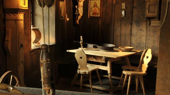 Das Museum Ladin Ćiastel de Tor Historischer Raum mit Webstuhl und hölzernen Stühlen vor einem Holztisch