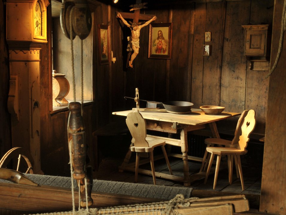 Das Museum Ladin Ćiastel de Tor Historischer Raum mit Webstuhl und hölzernen Stühlen vor einem Holztisch
