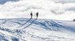 Schneeschuhwandern im Vinschgau Zwei Personen stehen auf einem schneebedeckten Hügel unter bewölktem Himmel