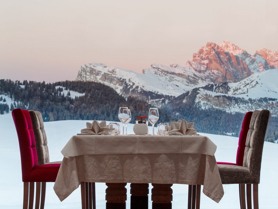 Gourmet-Urlaub in Südtirol: Genuss pur Eleganter gedeckter Tisch vor großem Fenster mit Blick auf verschneite Berge