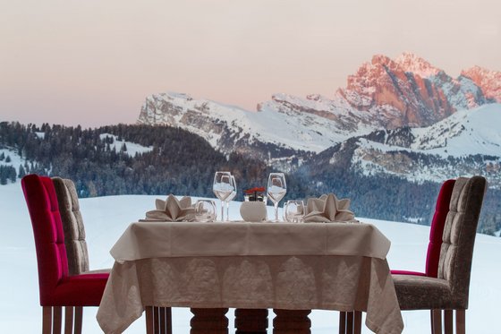 Boutiquehotels in Südtirol Eleganter gedeckter Tisch vor großem Fenster mit Blick auf verschneite Berge