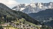 Hotels in St. Ulrich in Gröden – Südtirol-Urlaub vom Feinsten Dorf mit Häusern vor bewaldeten Hügeln und Felsgebirge im Hintergrund