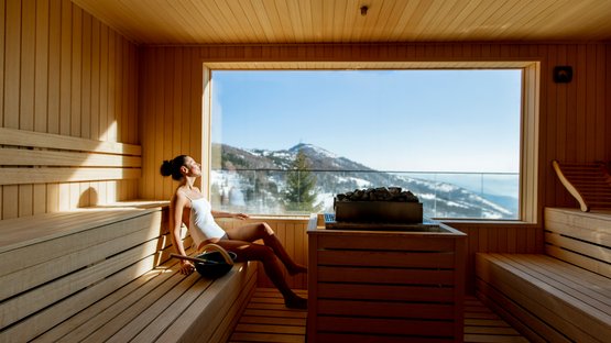 Die besten Wellnesshotels in Südtirol: Zeit für erholsame Stunden Frau entspannt in Sauna mit Bergblick durch großes Fenster