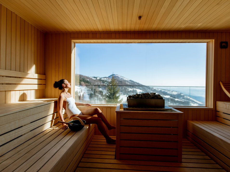 Hotel con spa in Alto Adige Donna rilassata in sauna con vista sulle montagne dalla grande finestra