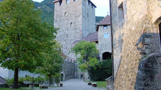 Hotel a Tirolo: la vostra meta di viaggio preferita Cortile di un castello medievale con muri di pietra e alberi