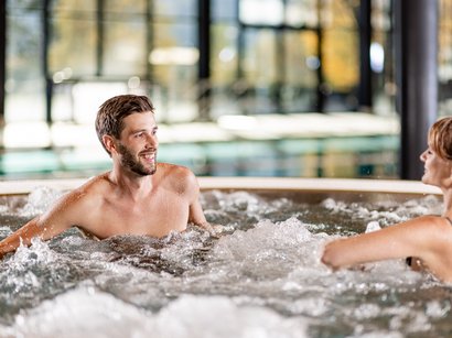 Die Hotels in Sterzing versprechen wunderbare Tage Mann und Frau entspannen in einem sprudelnden Whirlpool in einem Innenbereich