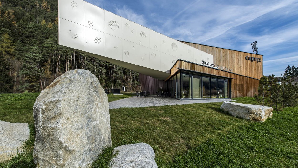 Capriz Feinkäserei Edificio moderno con facciata in legno e grandi pietre su prato verde