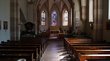 Hotels in Glurns: Urlaub in der kleinsten Stadt Südtirols Innenraum einer Kirche mit Holzbänken und bunten Buntglasfenstern am Altar
