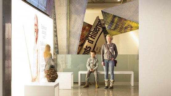 Das Südtiroler Archäologiemuseum Menschen in moderner Museumsausstellung mit leuchtendem Bildschirm und Bannern