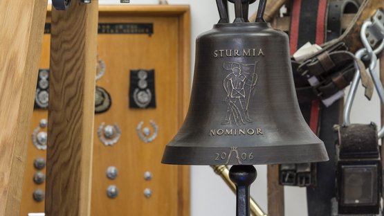 Il Museo dei Pompieri a Gais Uniforme dei pompieri, campana incisa e attrezzatura storica sullo sfondo