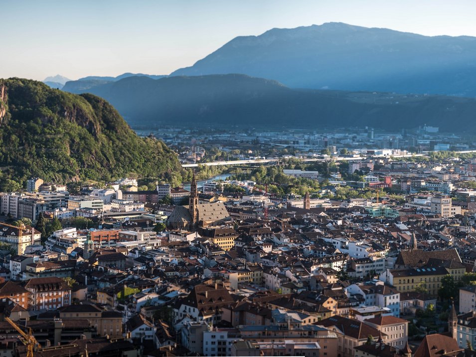 Funivia del Colle: la più antica funicolare del mondo Vista panoramica di una città con montagne sullo sfondo al tramonto