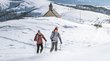 Ihre Hotels in Meran in Südtirol: Hotels im Meraner Land Zwei Wanderer mit Stöcken laufen durch schneebedeckte Berge bei sonnigem Wetter